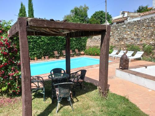 un patio con sillas y una mesa junto a la piscina en Casa Rural El Chorrillo Cazalla de la Sierra, en Cazalla de la Sierra