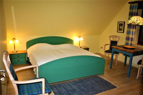 a bedroom with a green bed and a table and chairs at Haus Halligblick, Ferienwohnungen am Wattenmeer, Whg Oland in Dagebüll