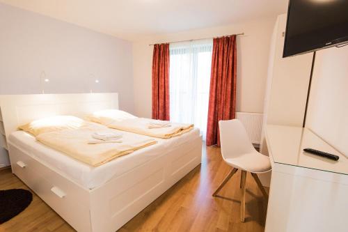 a white bedroom with a bed and a chair at Ostseebrise Reetdach 2 in Zingst