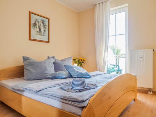 sypialnia z łóżkiem z niebieskimi poduszkami i oknem w obiekcie Strandstraße 51 Whg 1 w Zingst
