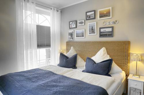 a bedroom with a bed with blue pillows and a window at Villa Vogelsang, Pier 6 in Zingst