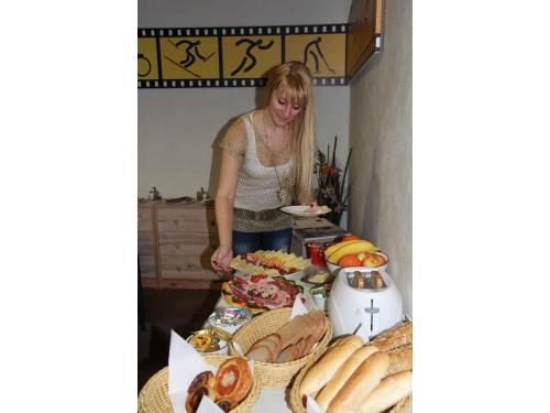 a woman standing in front of a table of food at Bed & Breakfast Penzion Brno in Brno