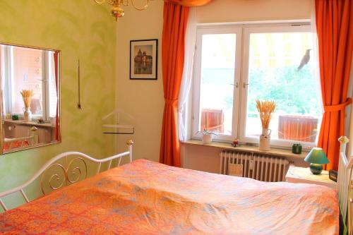 Schlafzimmer mit einem Bett mit orangefarbenen Vorhängen und einem Fenster in der Unterkunft Haus Strandfee - App 12 in Grömitz