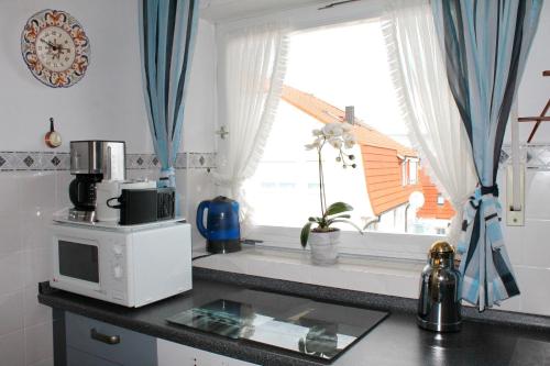 eine Küche mit einer Theke mit einer Mikrowelle und einem Fenster in der Unterkunft Haus Strandfee - App 12 in Grömitz
