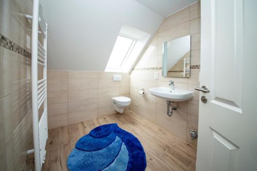 a bathroom with a toilet sink and a blue rug at Appartement Schleipanorama in Rabenkirchen-Faulück