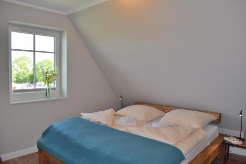 a bed in a white room with a window at Reethaus 3A in Staberdorf