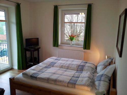 a bedroom with a bed and a window with green curtains at "Höper Mittelhof" Doppelzimmer Nr4 in Lemkendorf