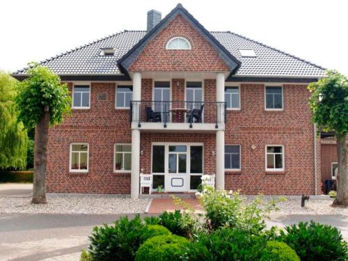 a red brick house with a balcony on it at "Höper Mittelhof" Doppelzimmer Nr4 in Lemkendorf