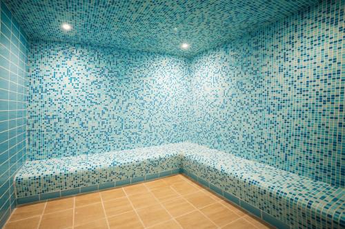 a bathroom with blue tiled walls and a bench at Swiss Blue Hotel - Hera in Jeddah