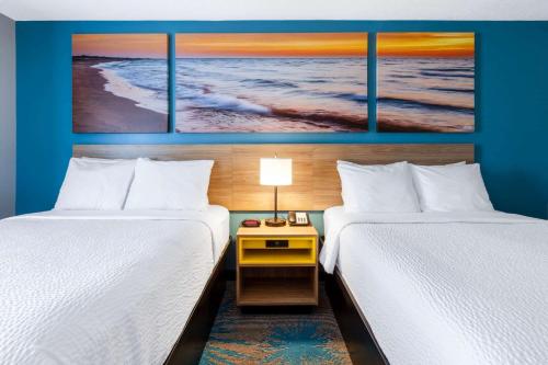 a hotel room with two beds and a table between them at Days Inn by Wyndham Sandusky Cedar Point in Sandusky