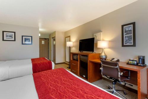 a hotel room with a bed and a desk with a computer at Comfort Inn Medford South in Medford