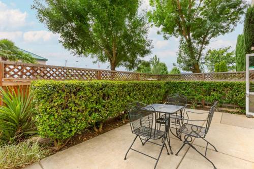 a patio with a table and chairs in front of a hedge at Comfort Inn Medford South in Medford