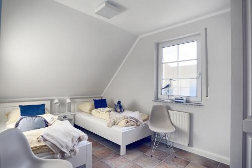 two beds in a white room with a window at 54 Grad Nord in Zingst