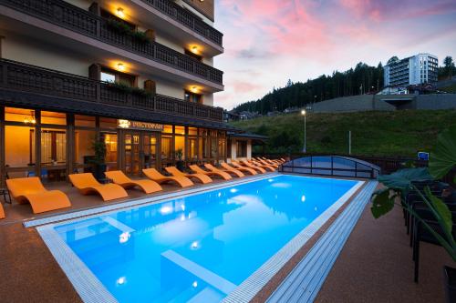 a large swimming pool with chairs and a building at Ganz & SPA in Bukovel