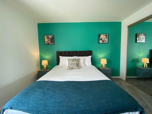 a bedroom with a large bed with a green wall at Principal Apartments - Merchant City in Glasgow