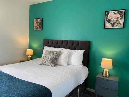 a bedroom with a bed with a blue wall at Principal Apartments - Merchant City in Glasgow