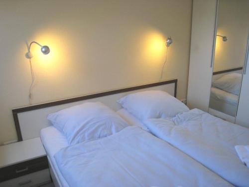 a bedroom with two beds with white sheets and two lights at Fehmarnstrand 78 App 9 in Staberdorf