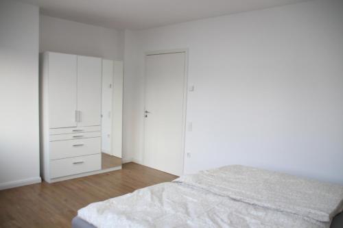 ein weißes Schlafzimmer mit weißen Schränken und einem Bett in der Unterkunft Casa Kronengarten Nr 1 in Hilden