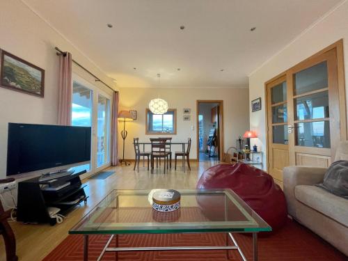a living room with a tv and a glass table at Casa Varanda do Mar in Capelas