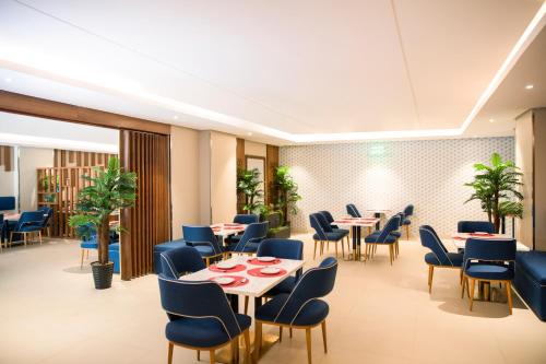 a restaurant with tables and chairs and plants at Swiss Blue Hotel - Hera in Jeddah