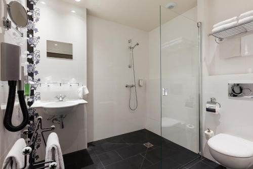 a white bathroom with a sink and a shower at Hôtel Aurore Paris Gare de Lyon in Paris