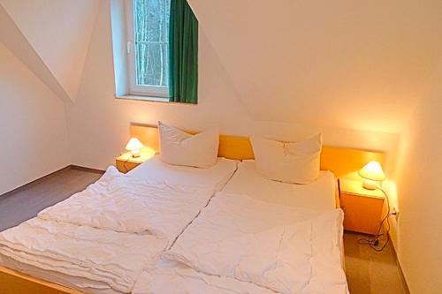ツィングストにあるAm Deich 46のベッドルーム1室(白いベッド1台、ランプ2つ付)
