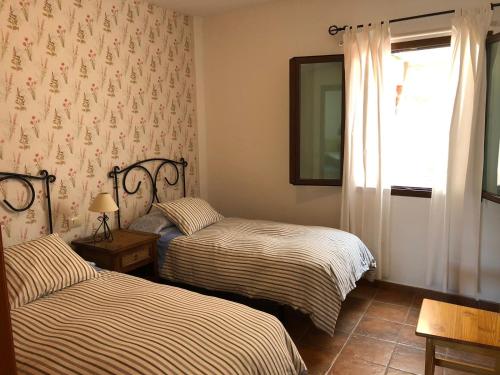 a bedroom with two beds and a window with curtains at VV El Almendro in Tejeda