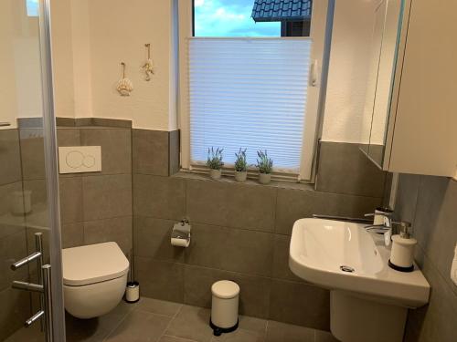 a bathroom with a sink and a toilet and a window at Ferienwohnung 2404 App 1 in Burhave in Burhave