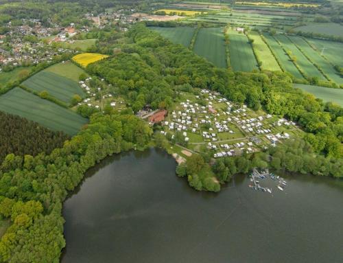 an aerial view of a lake with trees and houses at Baumzelt in Wittenborn