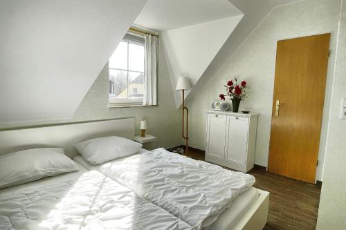 - une chambre avec un lit blanc et une fenêtre dans l'établissement Am Deich 47, à Zingst