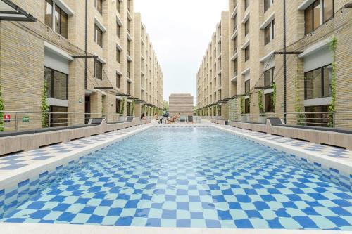 a swimming pool with a blue and white checkered floor between buildings at LivinnX Barranquilla in Barranquilla
