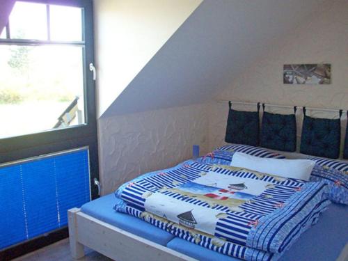um quarto com uma cama com um cobertor azul e branco em "Leuchtturm" em Fuhlendorf