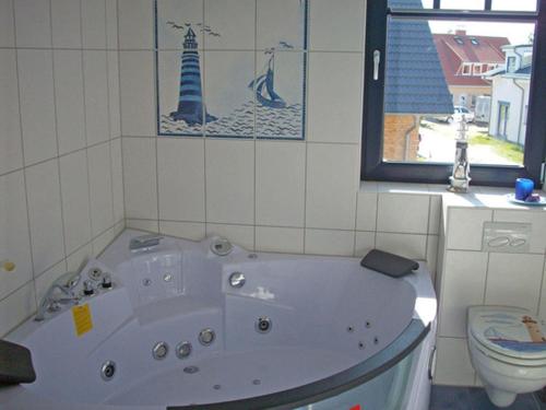 a bath tub in a bathroom with a toilet and a window at "Leuchtturm" in Fuhlendorf