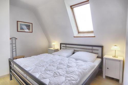 um quarto com uma cama com lençóis brancos e uma janela em Haus Havelland em Zingst