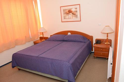 a bedroom with a purple bed with two lamps and a window at HOTEL OAZA in Štip