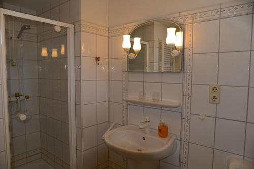 a white bathroom with a sink and a mirror at Ferien unterm Reetdach Whg 03 in Oevenum