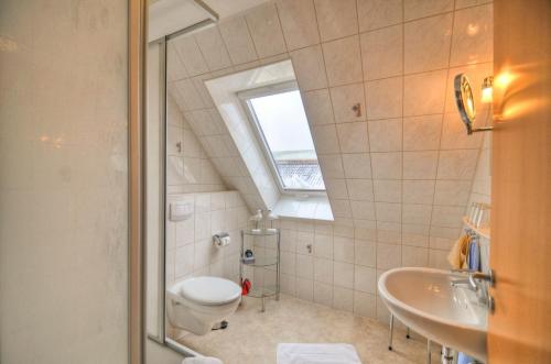 ein Bad mit einem WC, einem Waschbecken und einem Fenster in der Unterkunft Ferienwohnung Sewald in Wulfen auf Fehmarn