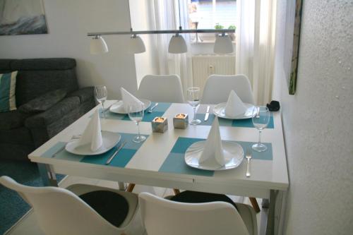 a dining room table with white chairs and a table with wine glasses at Strandstraße 21 Whg 5 in Zingst