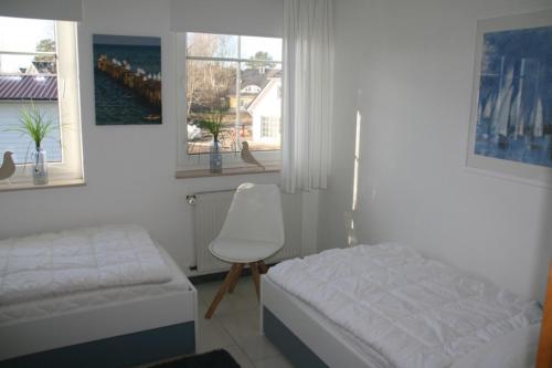 a bedroom with a bed and a chair and two windows at Strandstraße 21 Whg 5 in Zingst