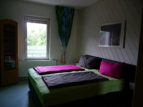 een slaapkamer met een bed met paarse lakens en een raam bij Wohnung "Doppelspitze" in Hohenhameln
