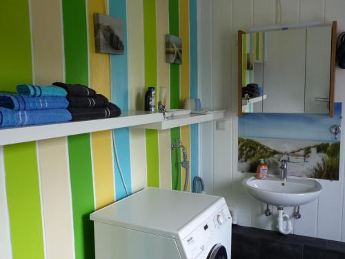 een badkamer met een wastafel, een spiegel en een wasmachine bij Wohnung "Doppelspitze" in Hohenhameln