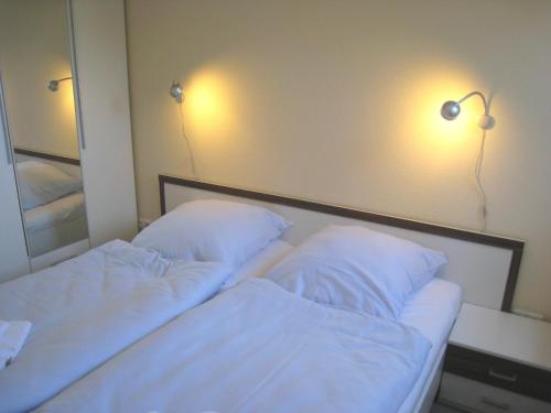 1 dormitorio con 2 camas y 2 luces en la pared en Fehmarnstrand 78 App 14, en Staberdorf