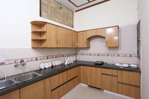 kuchnia z drewnianymi szafkami i zlewem w obiekcie SAI HOME w mieście Dehradun