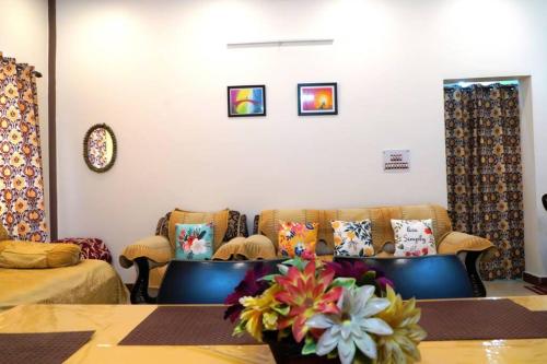 a living room with couches and a table with flowers at SAI HOME in Dehradun