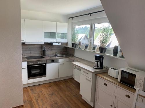 a kitchen with white cabinets and white appliances at Ferienwohnung Bergstraße in Winterberg