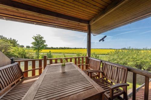 a wooden table on a deck with a view of a field at "Ferienhof Seelust" Ferienwohnung 5 in Gammendorf