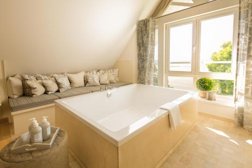a large white bath tub in a room with a couch at Alter Meierhof Glücksburg in Glücksburg
