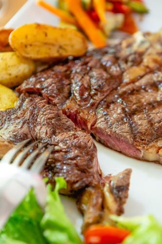a plate of steak and vegetables with a fork at Auberge U n'Antru Versu in San-Gavino-di-Carbini