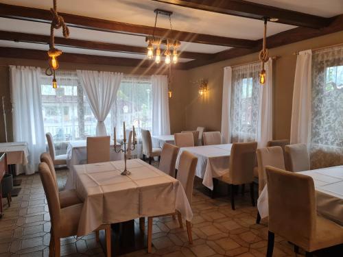 a restaurant with white tables and chairs and windows at Gasthof Barlida in Lainach