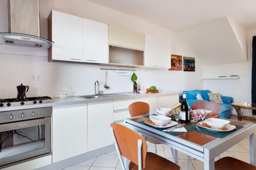 a kitchen with white cabinets and a table with chairs at Granito's in Monte Petrosu